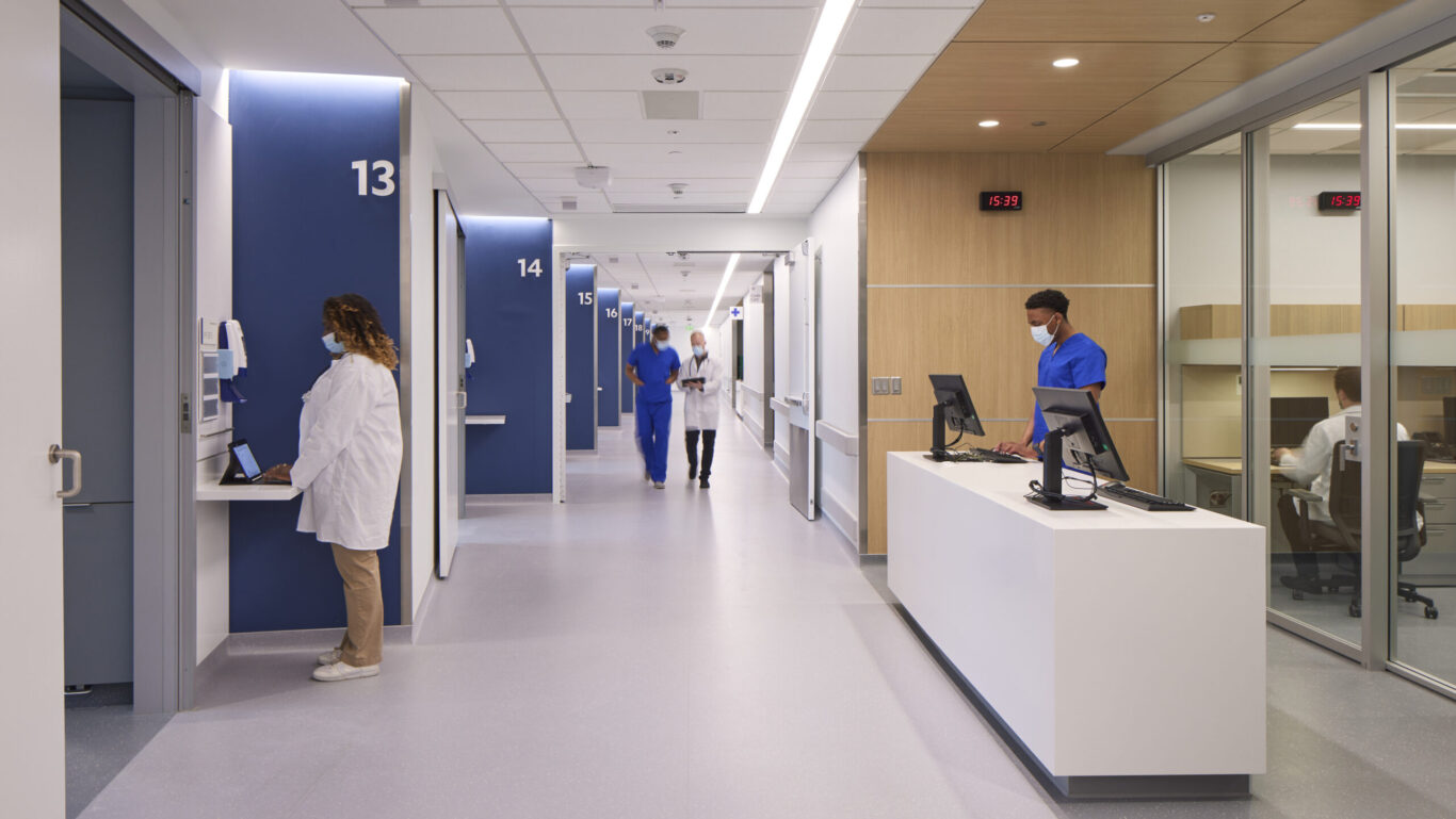 Slide 1 of 7, Interior view of nurse stating and inpatient care corridor. 